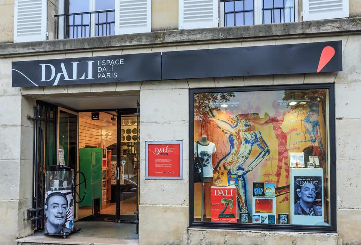 A front view of the entrance to Dali museum. The museum name is displayed on a black shop banner and there is a squared window with artwork displayed