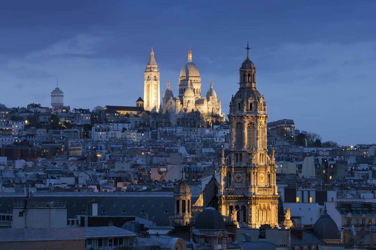 A landscape view of Sacre coeur (Basilica of Sacred heart), Montmartre and Sainte-Trinite at night