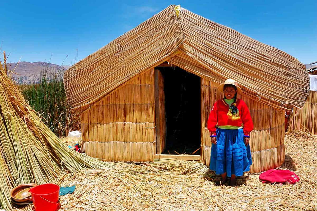Young local girl on a floating Uros island standing in front of her home