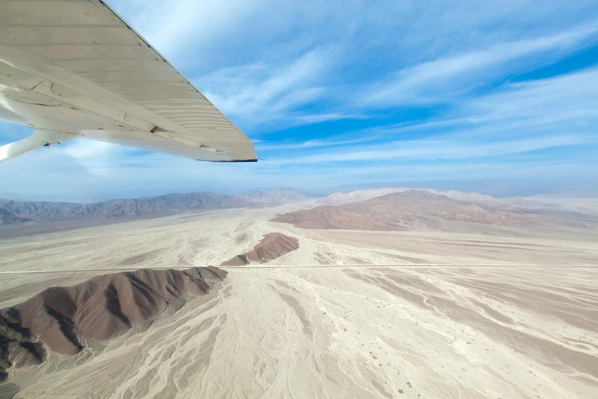 View from a plane wing flying over flat desert