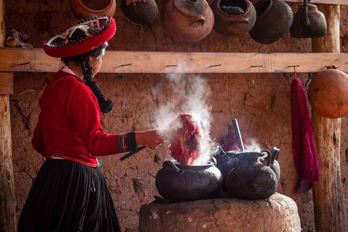 View of a girl showing tourists the process of dyeing alpaca fur to make yarn for weaving.