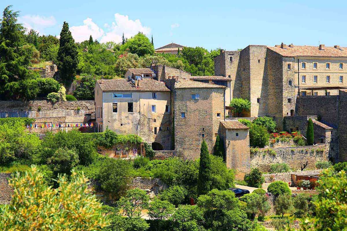 Stone village buildings surrounded by greenery on a hill top