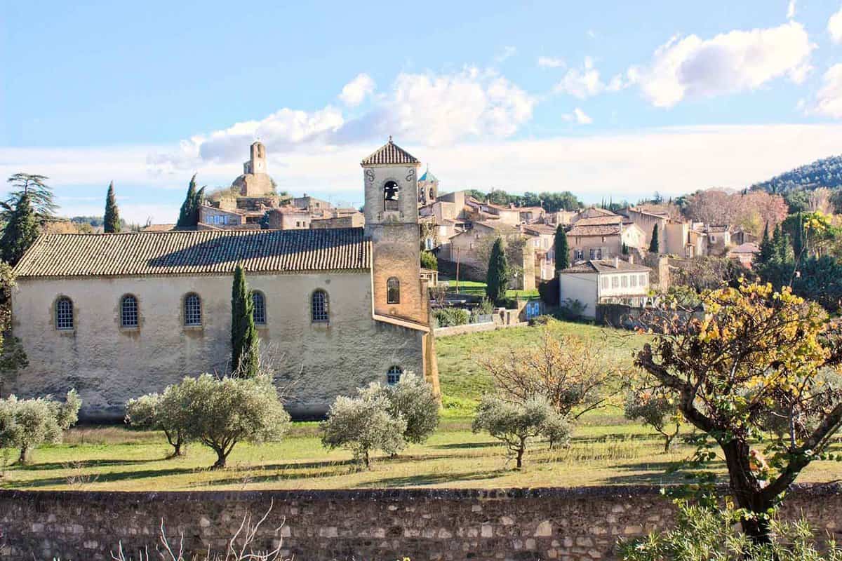 View of an old village in the Luberon region, southern France. Old church and houses with trees and sunshine.