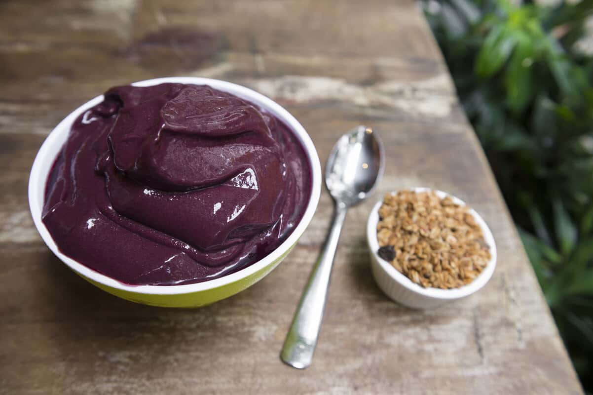 Bowl of purple paste with spoon and nuts