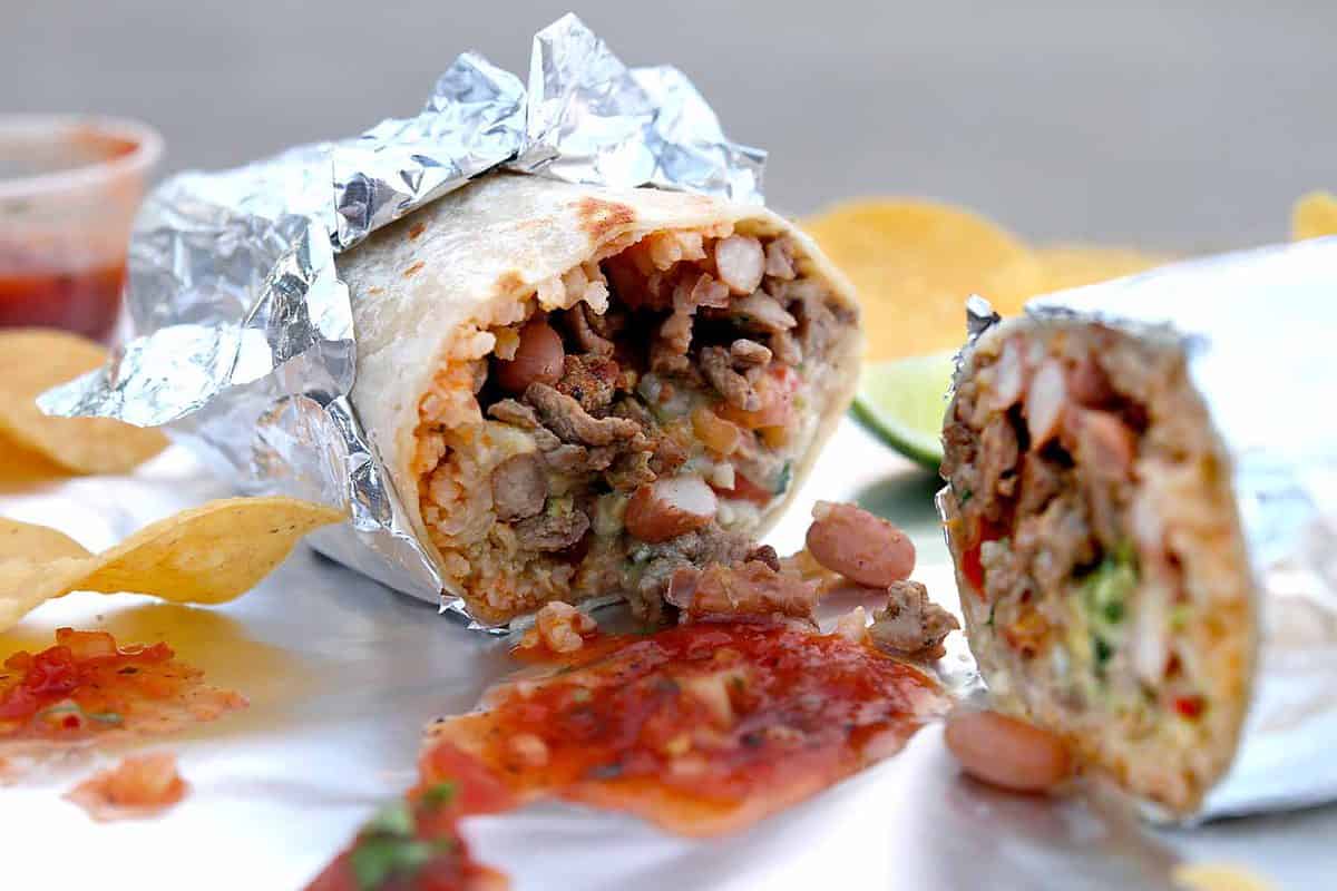 California Style Burrito Wrapped in Foil Surrounded by Chips and Salsa