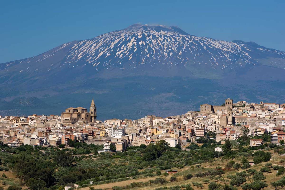 view of dwellings in the city of Regalbuto in Sicily, on background the volcano Etna partly snowy