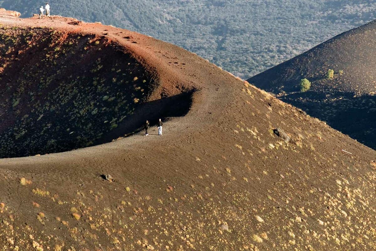 tourists on edge of volcanic Mount Etna's cone