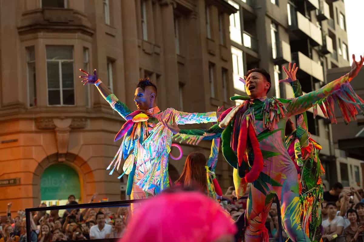 2 men on top of a loat wearing colourful, skin-tight costumes.