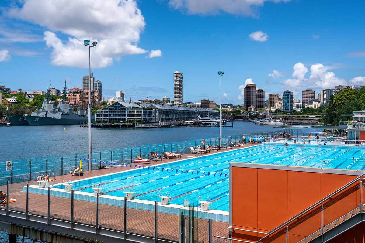 An outdoor pool on the edge of the harbour in front of Sydney's skyline.