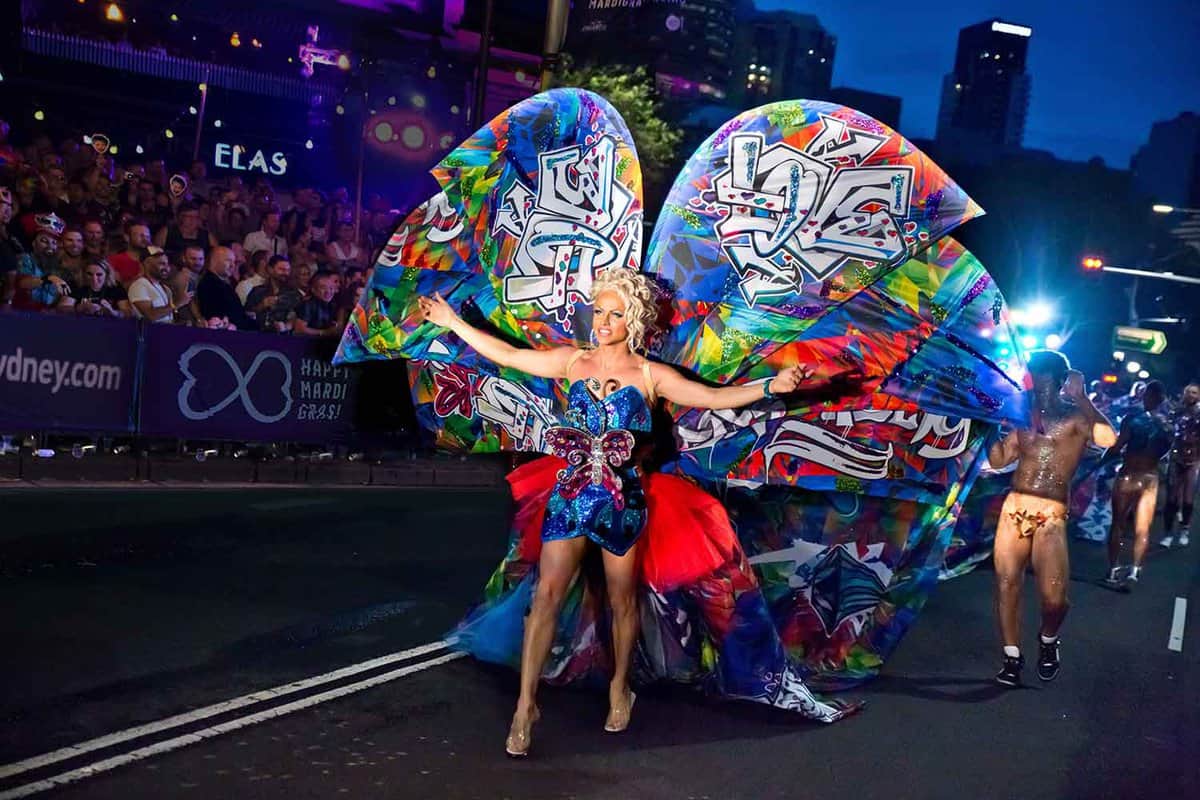 A person in an extravagant dress with wings. during a parade.