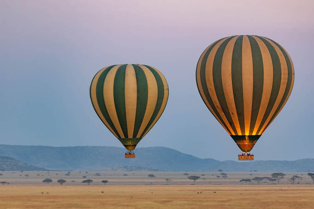 two stripey hot air ballooons drifting over the plains