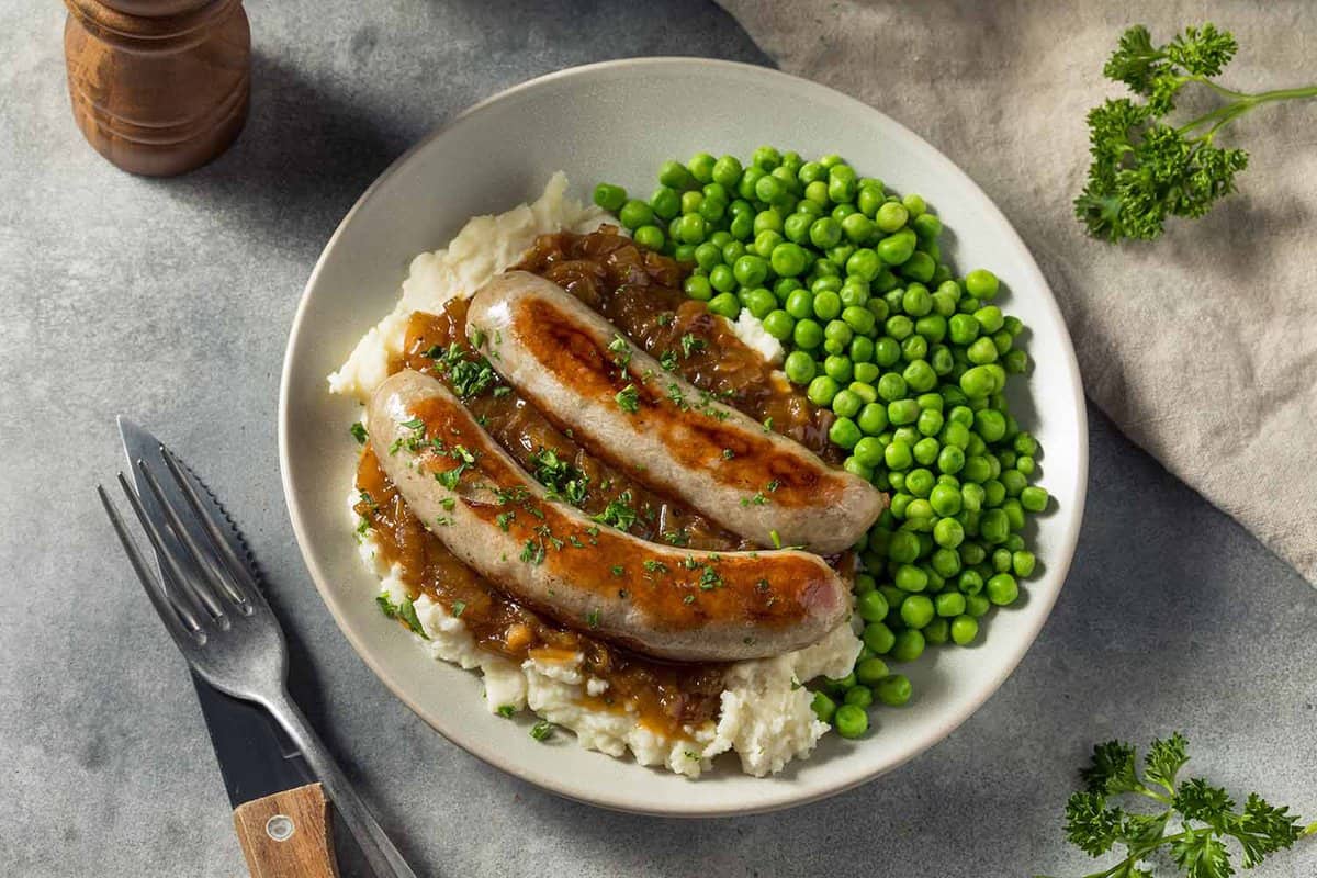 sausages on bed of mash potatoes with peas