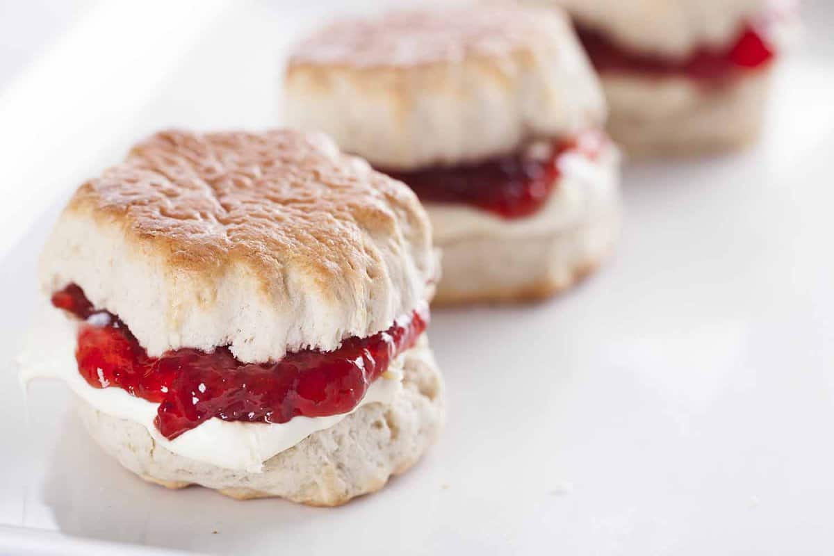 close up of a fresh scone filled with jam and cream