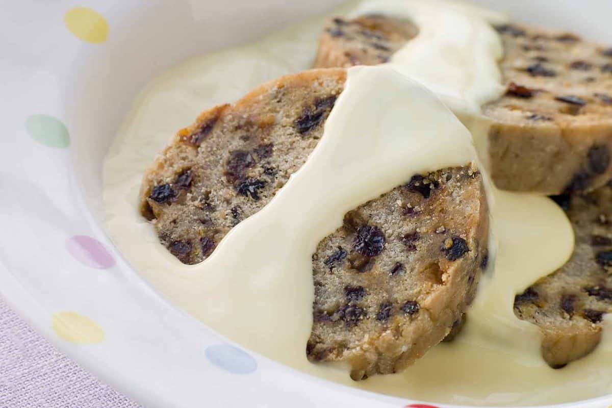 custard dribbled over spotted dick dessert