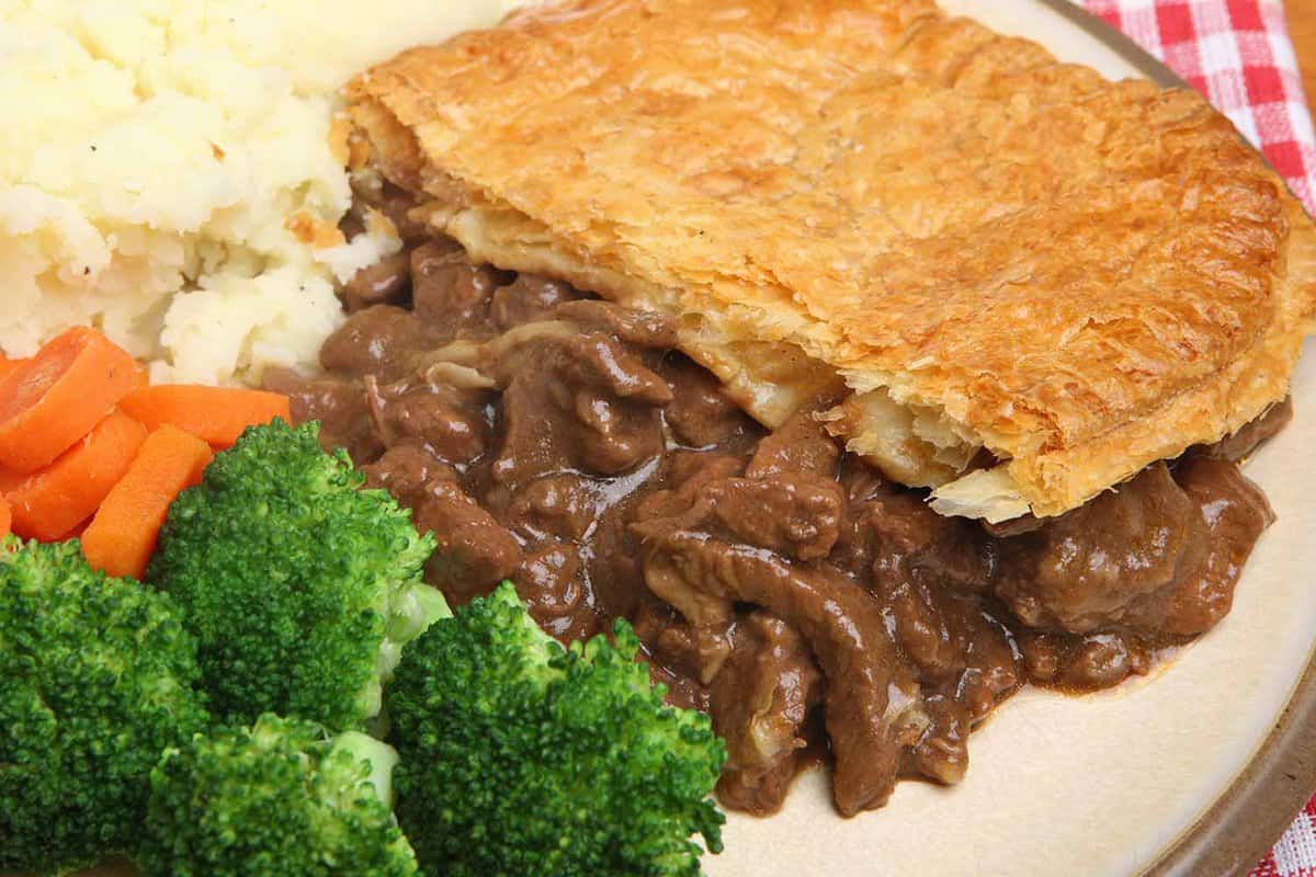 half a steak and kidney pie with vegetables