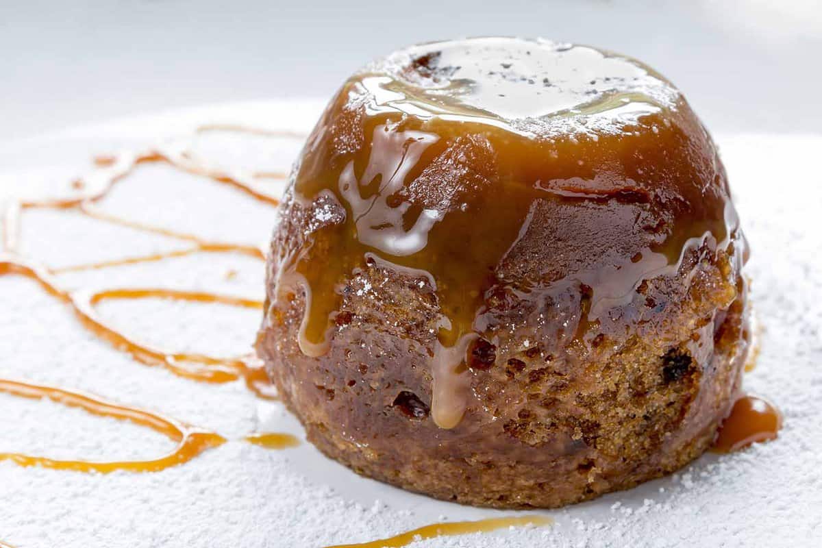 close up of a small sticky toffee pudding covered in treacle