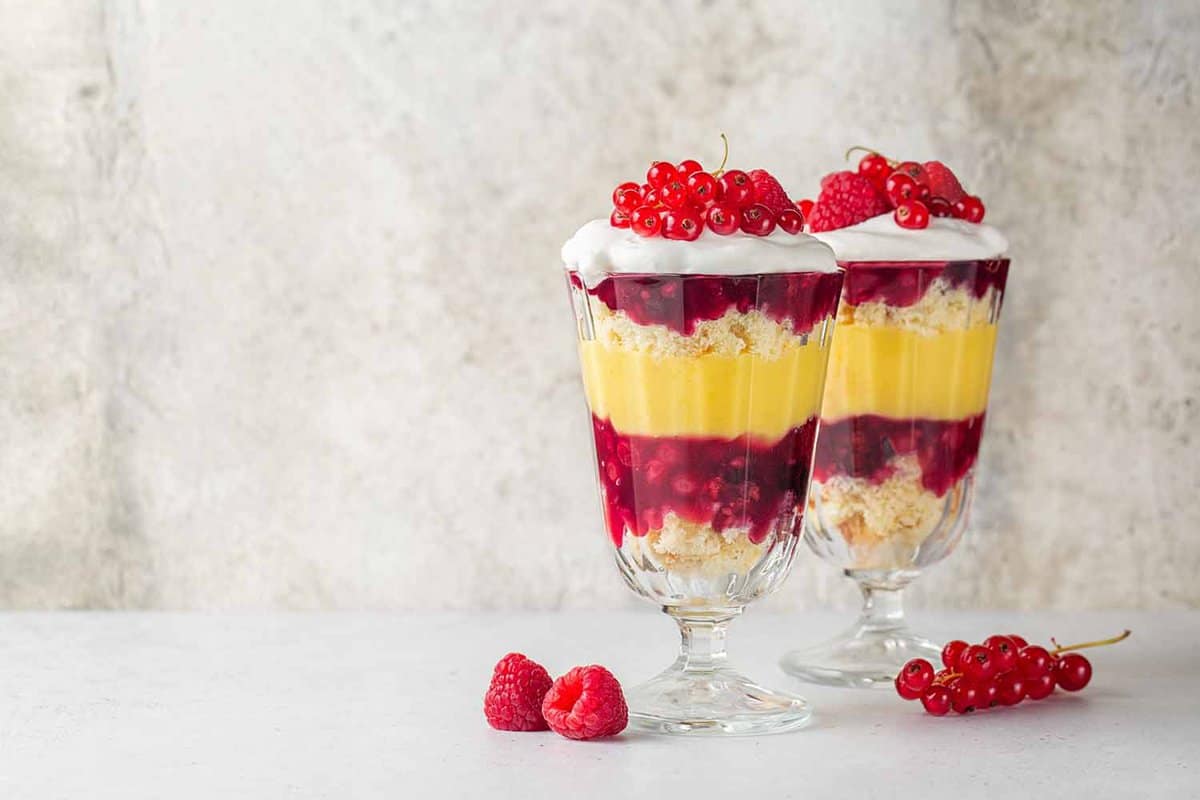 two glass trifle flutes filled with striped layers of cream and fruit
