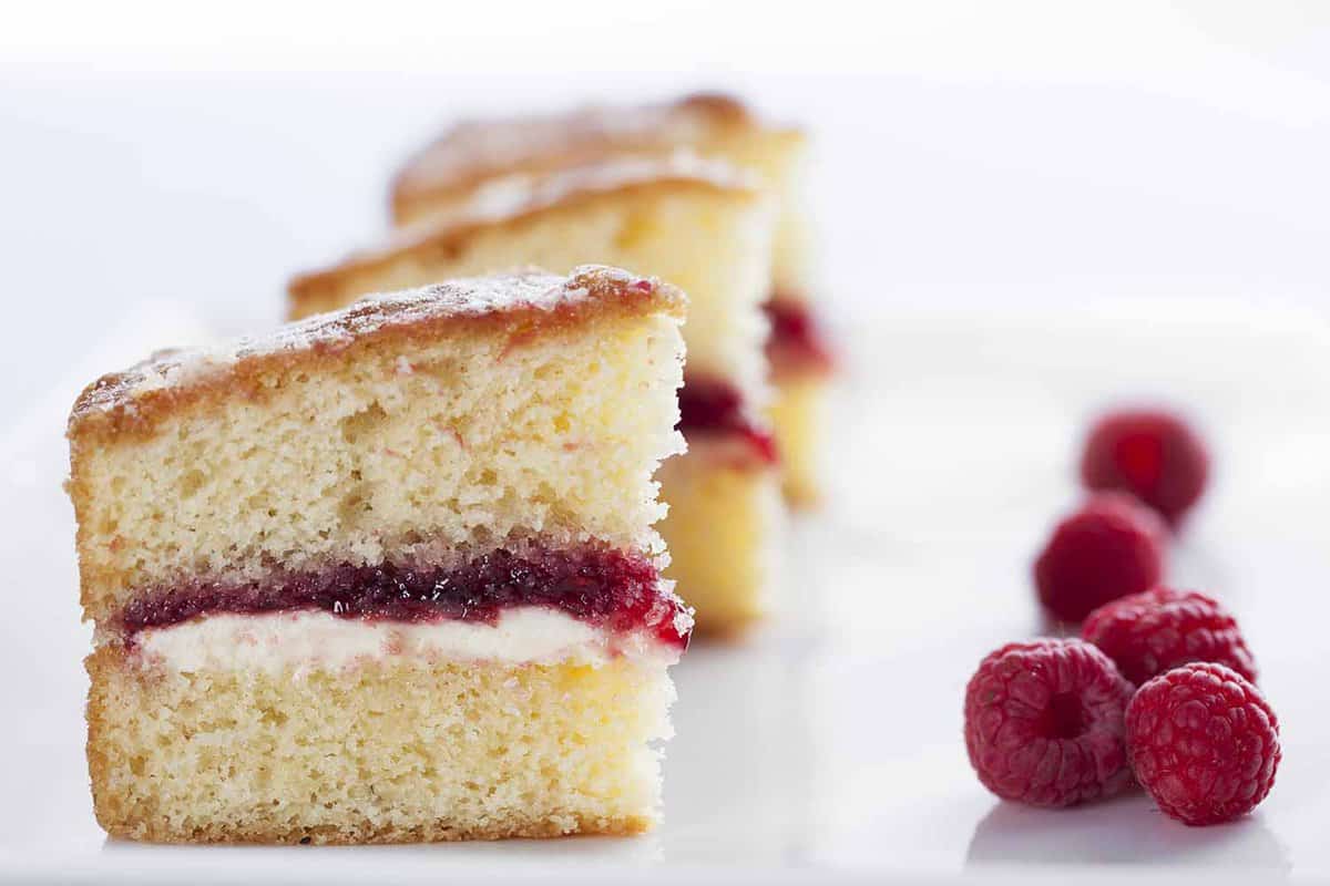 close up of slice of Victoria Sponge with some raspberries