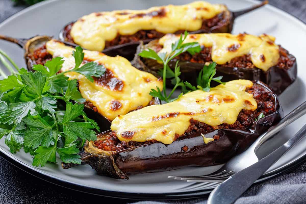 close up of a plate of Papoutsakia - Greek,Stuffed,Eggplants,With,Ground,Beef tomatoes,,Topped,With,Bechamel