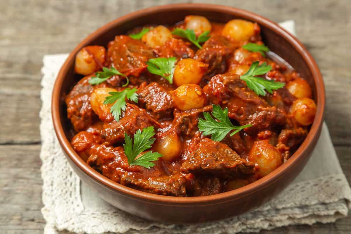 close up of a dish of beef Stifado - A pot stew with tomatoes, red wine and pickling onions