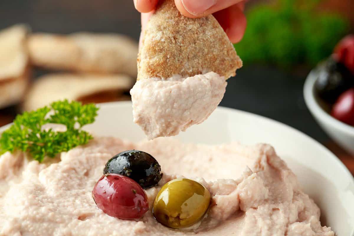 close up of a Taramasalata dip with olives and pita bread
