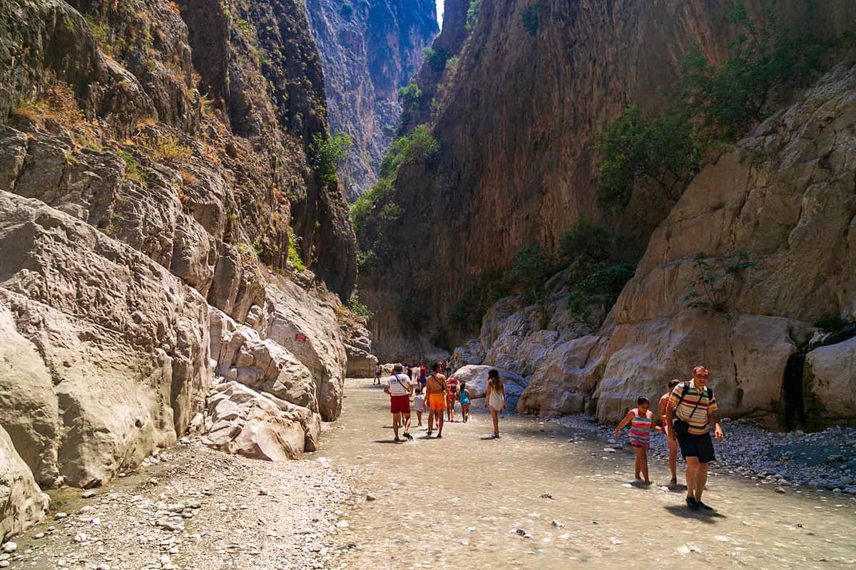 People walking through shallow water at the bottom of the canyon