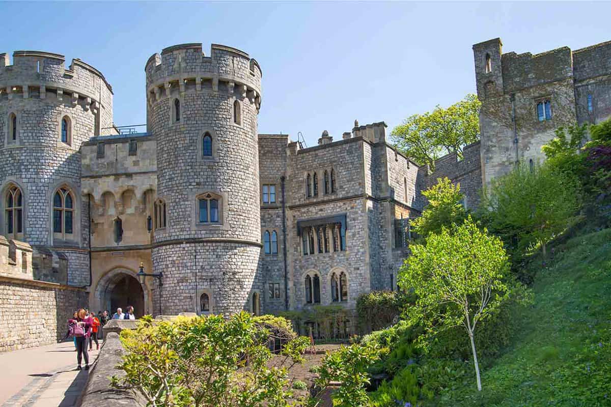 A side view of a hill with trees and bushes, where Windsor Castle can be seen in the background. Windsor Castle is official Residence of Her Majesty The Queen and hostage of Prince Harry and Meghan Markle wedding on 19 May 2018.