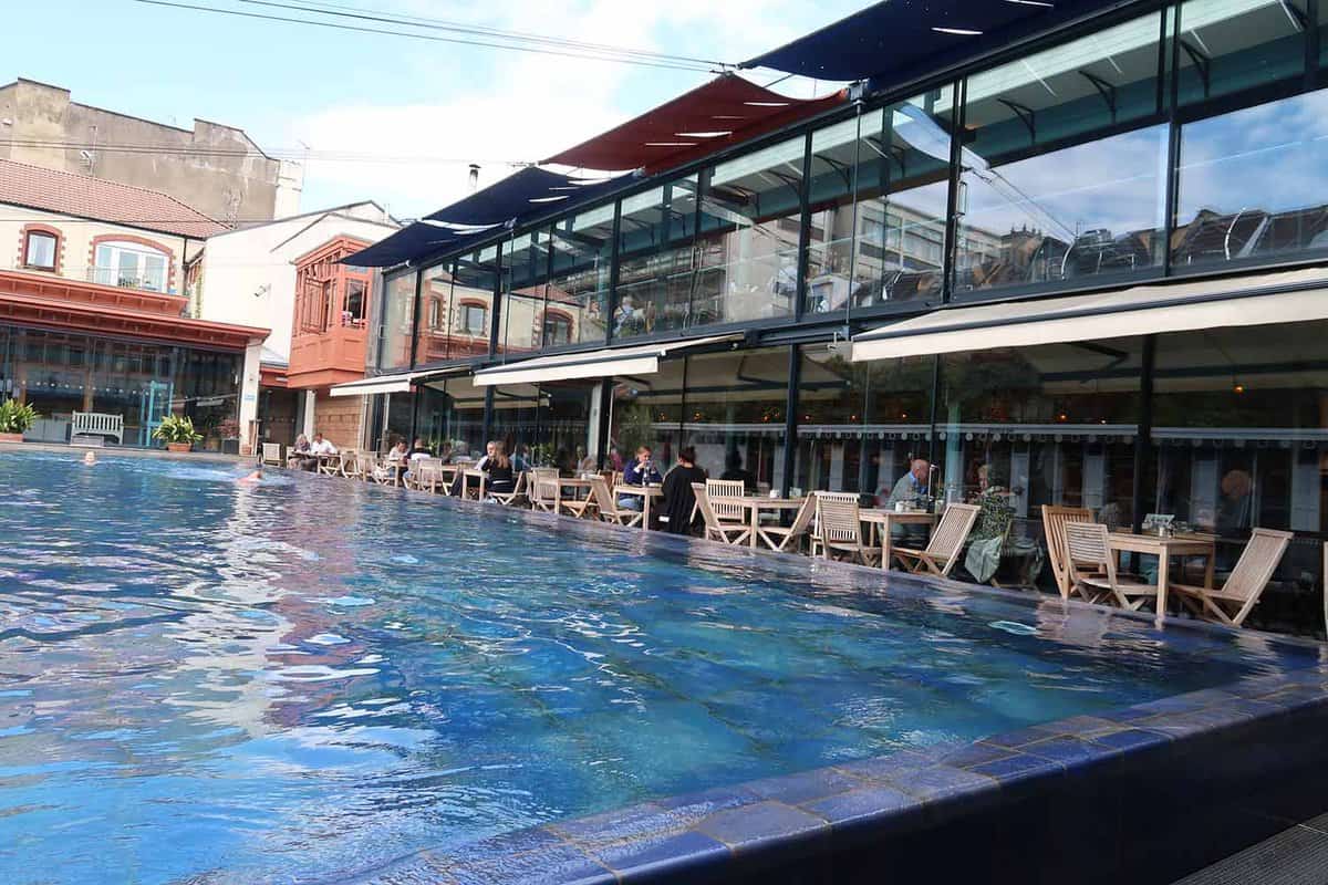 interior of the Lido, showing a pool with cafe tables around it and people eating