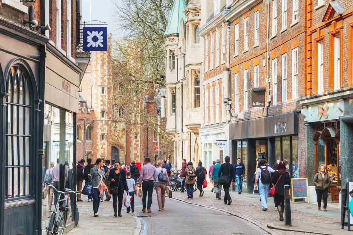 Shoppers walking down a busy, pedestrianised high street lined with shops