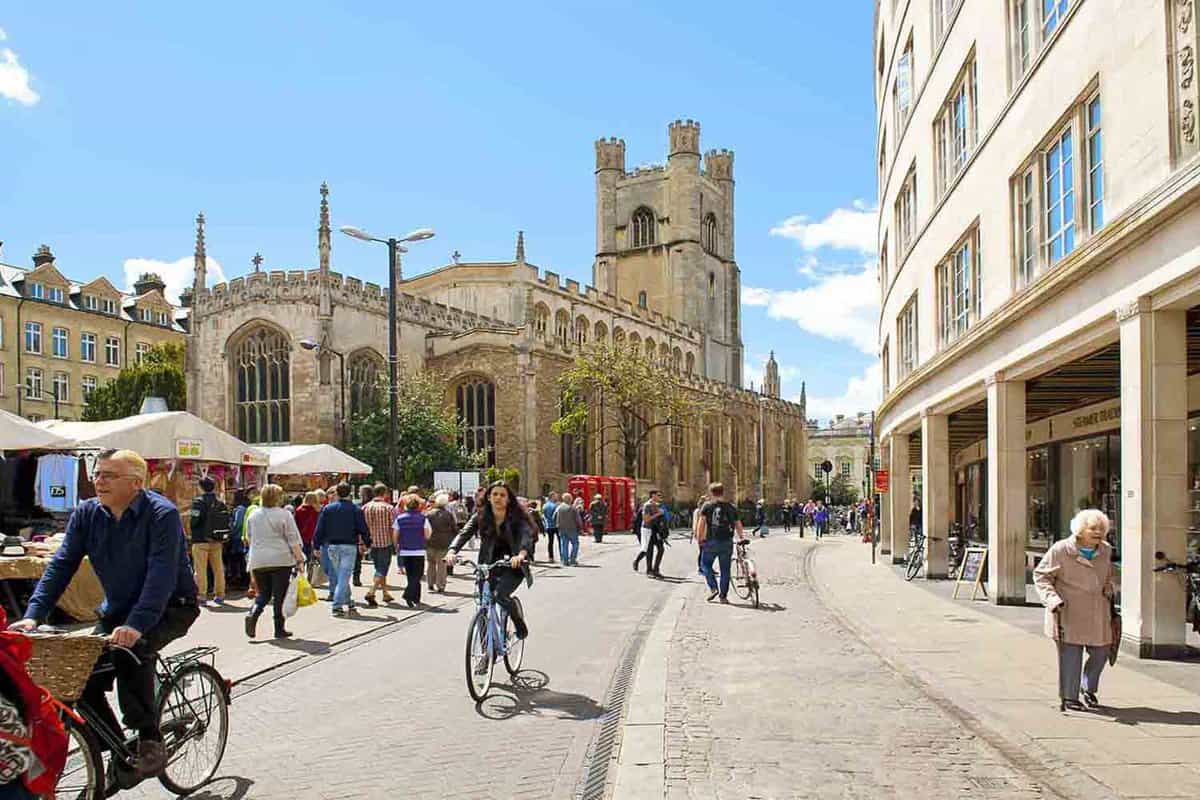 Photo of Market Square and church in central Cambridge with cyclists riding by