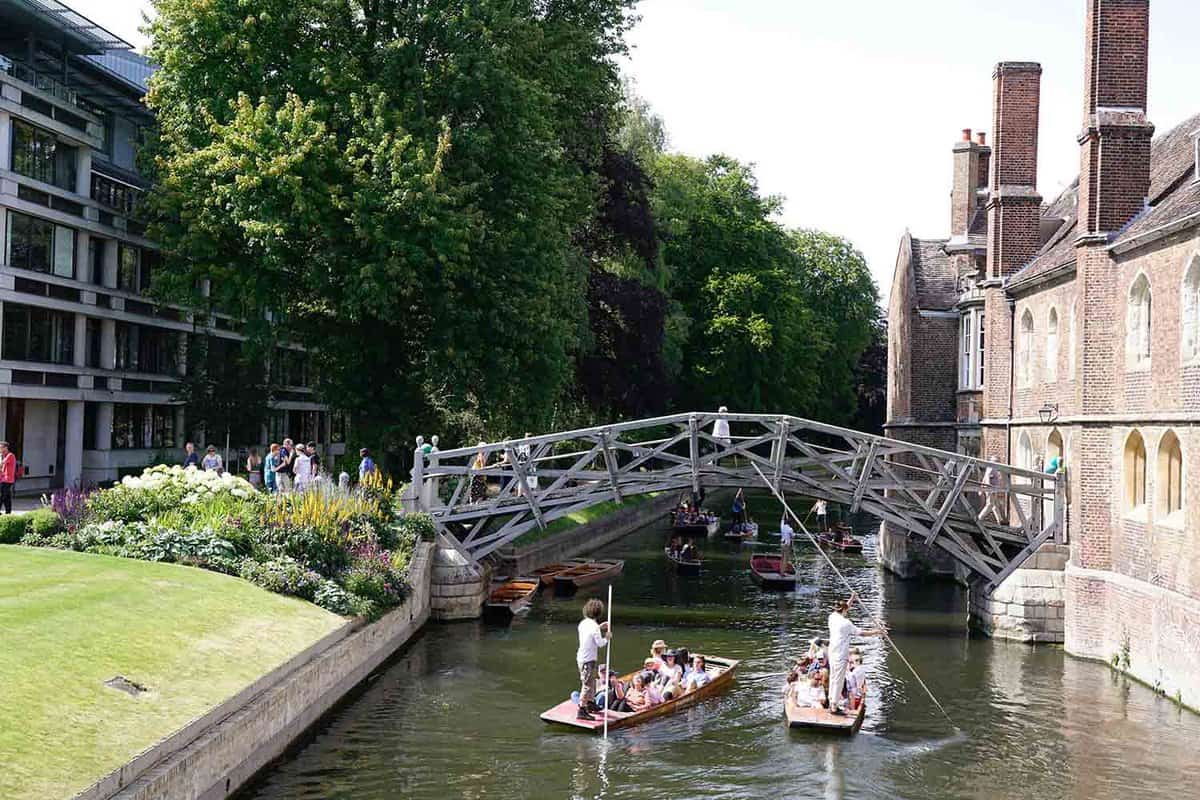 Tourists punting on River Cam with the Mathematical Bridge in the background