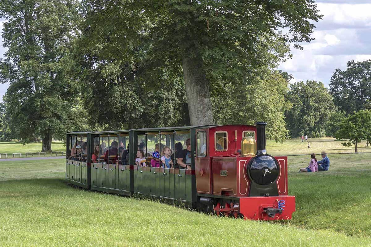 A toy train filled with tourists driving through the gardens