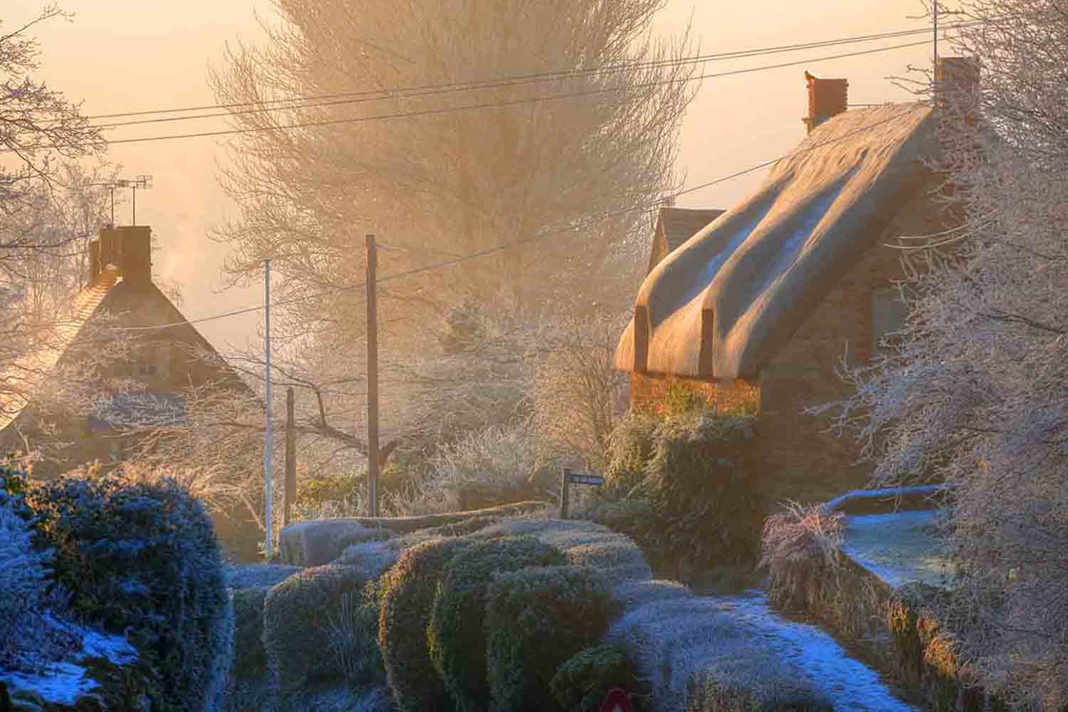 Silhouettes of cottages on a misty day. Winters morning in the Cotswold village of Ebrington, Gloucestershire