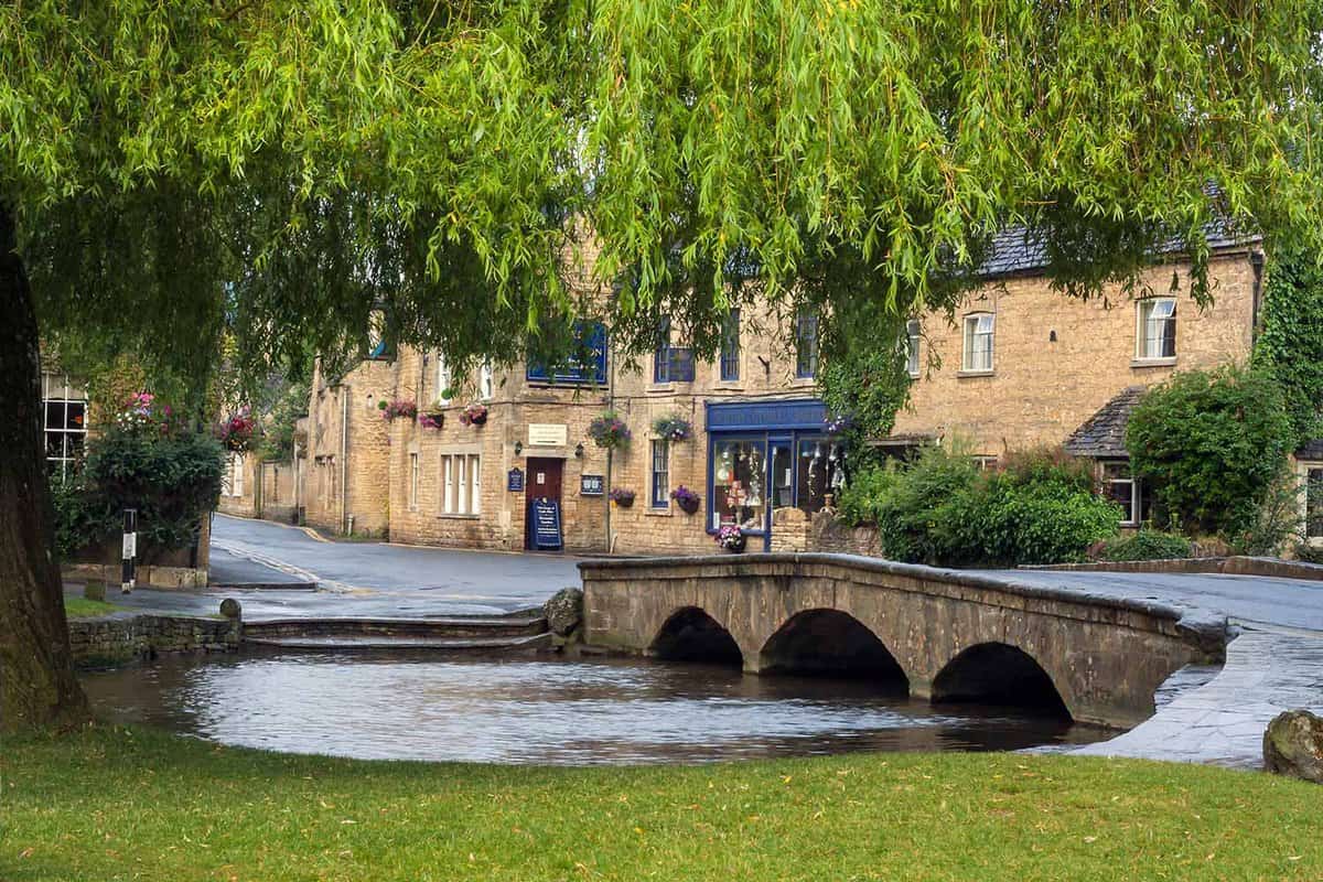 View over the River Windrush at Bourton-on-the Water in the Cotswolds. A small river running under a small bridge in the centre of the village