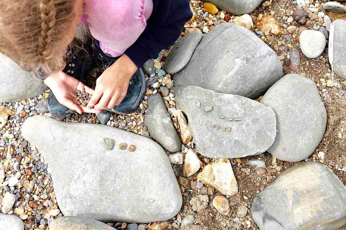 A photo showing the top view of a young girl fossil hunting at Charmouth beach,Dorset. England, on the Jurassic coast, UNESCO world heritage site. Where 140 million year old fossils can be found washed up on the beach at low tide.