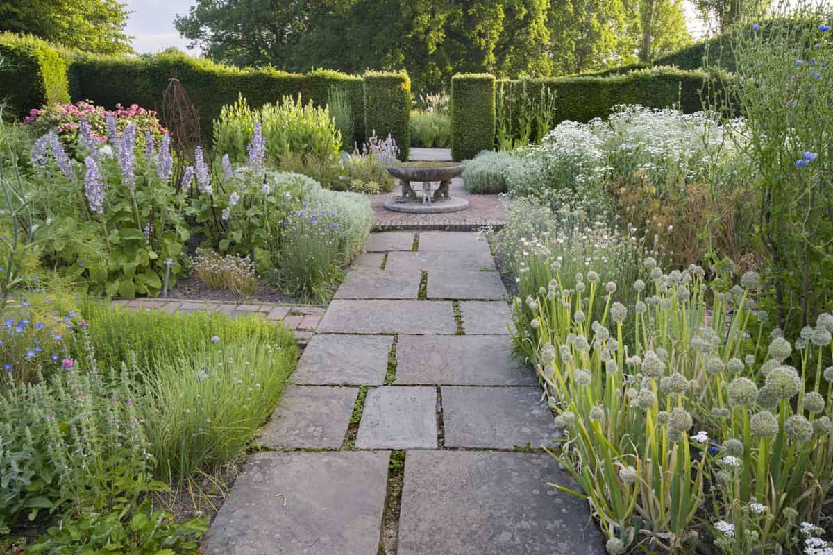 A close up of the brickwork designed as a pathway through the Herb Garden at Sissinghurst Castle Garden. There is small arrangements beside this footpath of plants and flowers