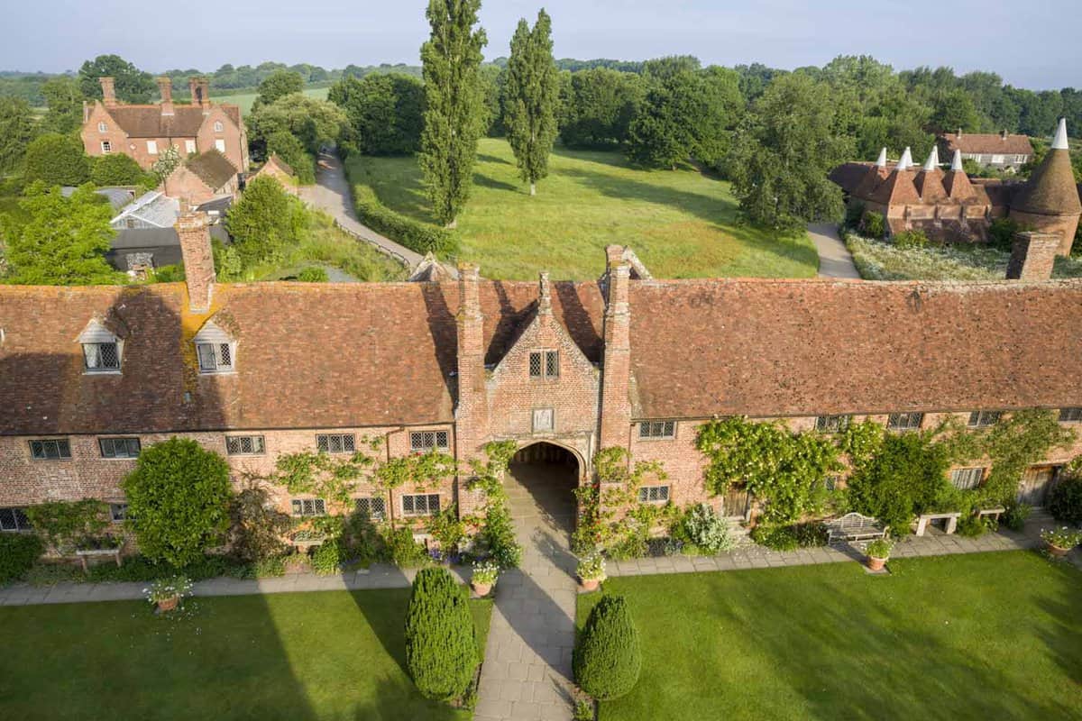 An overview of The Lower Courtyard from the Tower at Sissinghurst Castle Garden. The courtyard stretches horizontally with a small archway in the centre for a footpath that runs vertically.