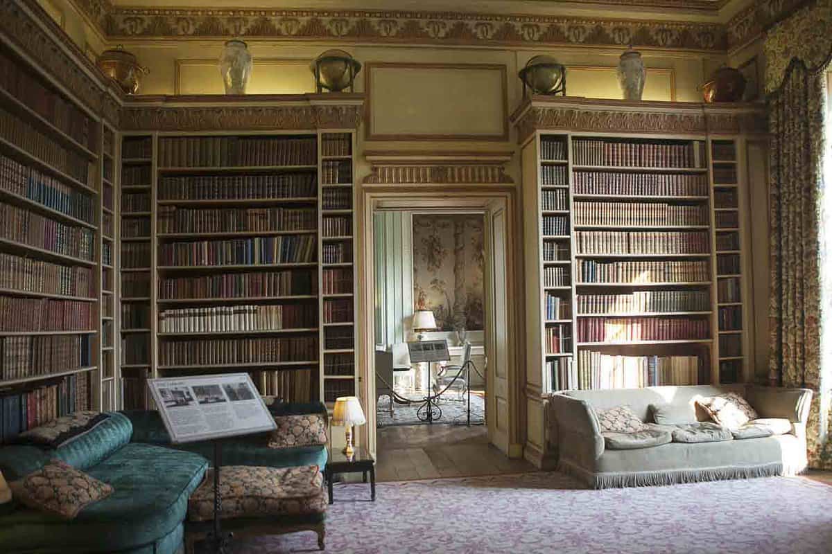 A Library room inside the castle with high bookshelves and two family size large sofas