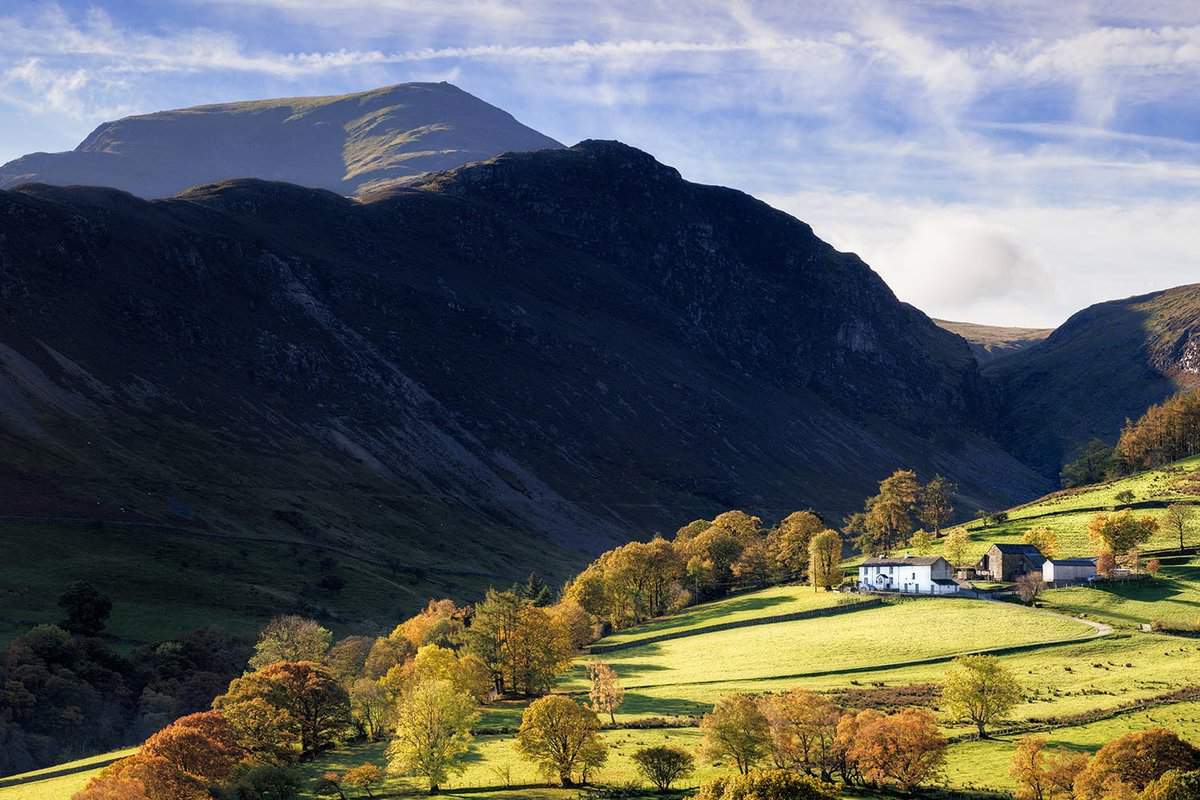 Sunlit farm below the dramatic mountains of the Lake District, England.