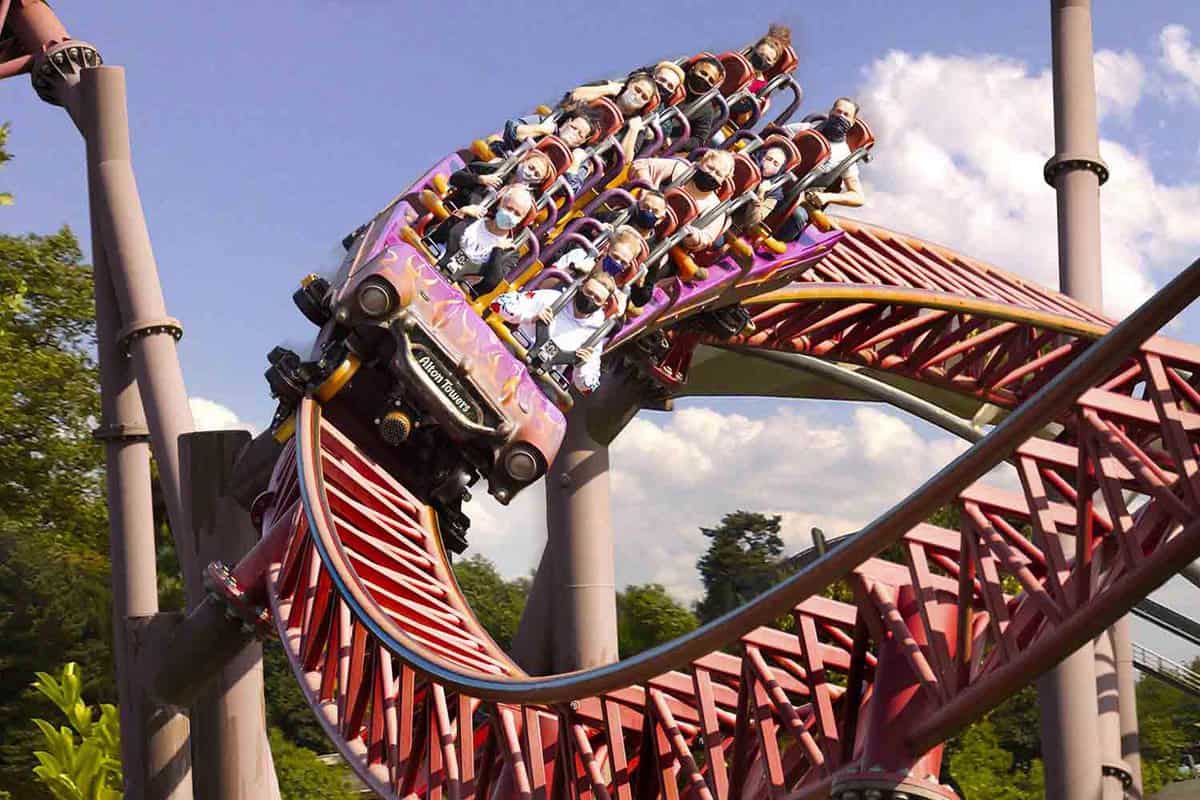 A red rollercoaster ride packed with face masked passengers