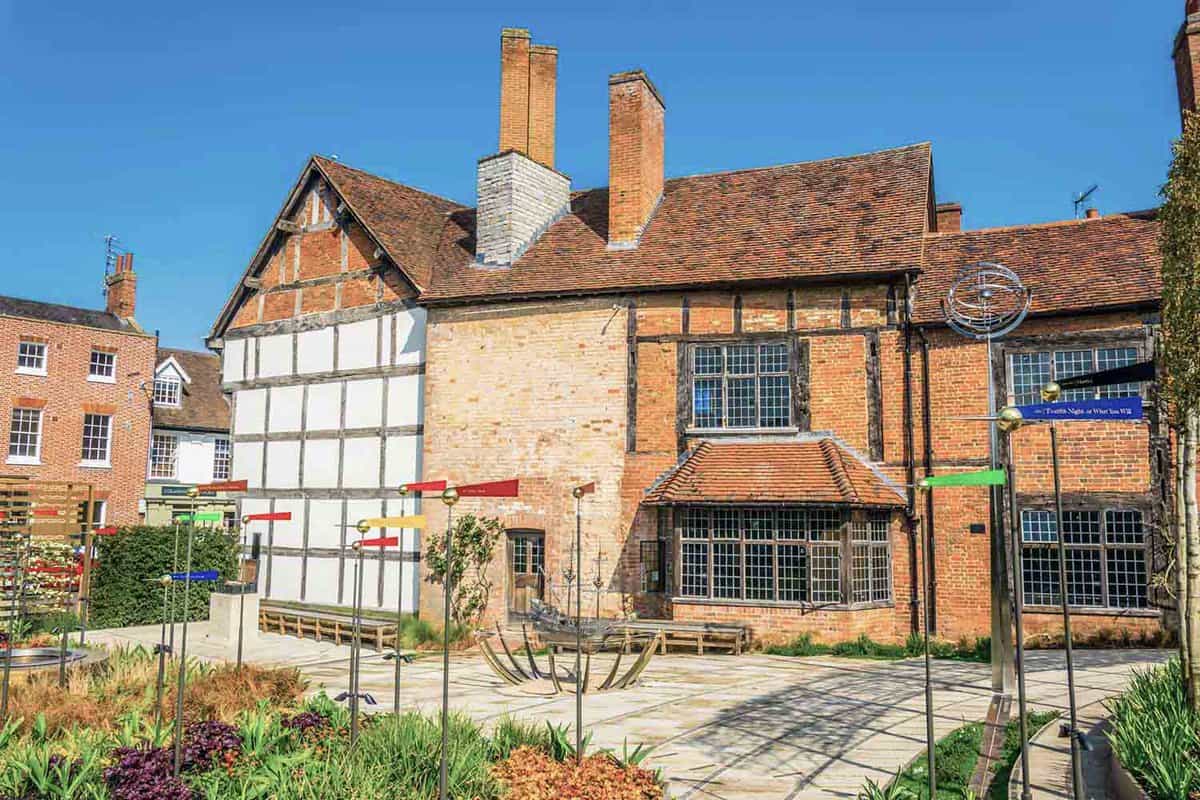 View of the New Place in Stratford upon Avon where William Shakespeare lived. Tall brick building with a small garden on around the front entrance