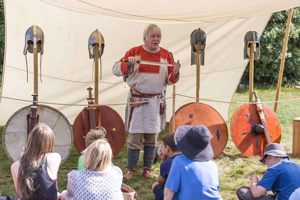 An Anglo-saxon history lesson, where children are sat down learning about the history with Anglo-saxon helmets and armour on display