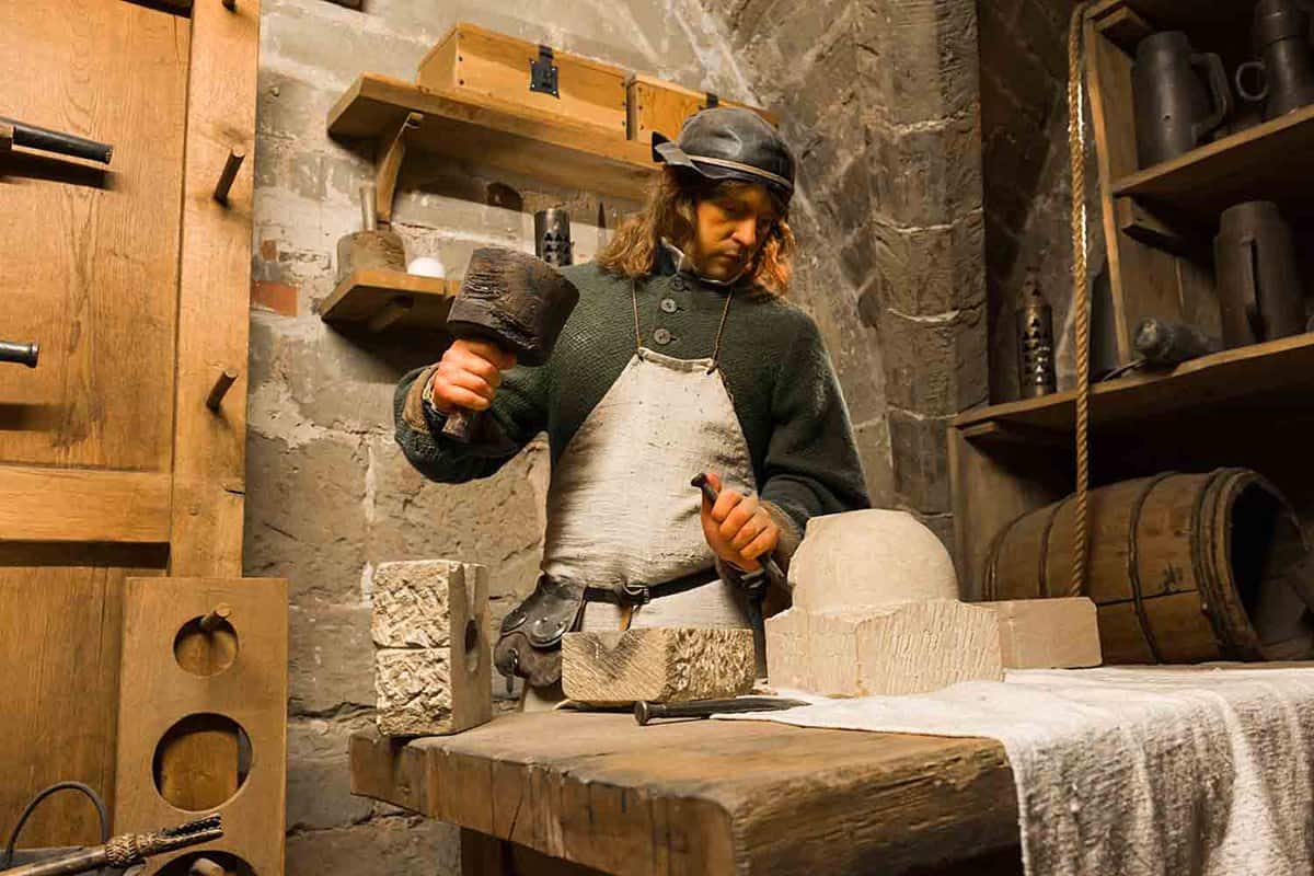 Wax figures enact a medieval stone mason scene inside the castle