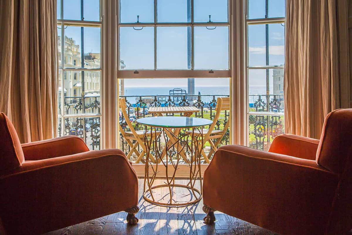 Two pale coral coloured armchairs facing a terrace window with a view of the seafront