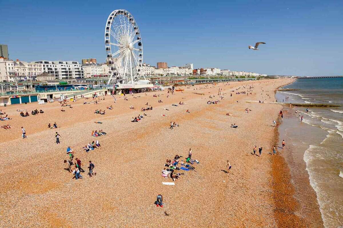 View along the Brighton Beachfront with the Ferris Wheel, promenade, and vacationer on shingle beach pictured from the Brighton Palace Pieron a sunny summer day