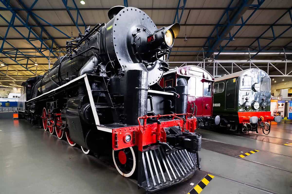 Black steam locomotive with a red trim inside a large warehouse