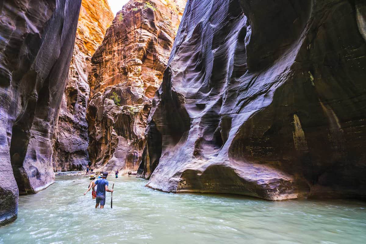 Person walking down a stream in a high-walled canyon