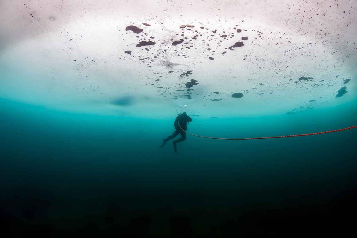 Single scuba diver under the ice in a lake at Tignes