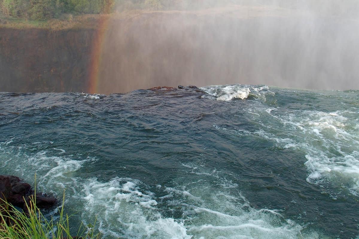 Devil's Pool filled with water looking across the gorge. with a rainbow