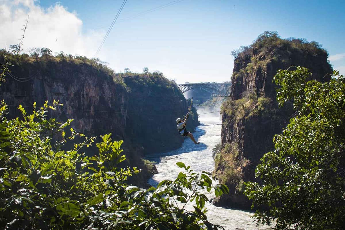 A dramatic shot of the Zambezi river with a person on the zip-line in the distance